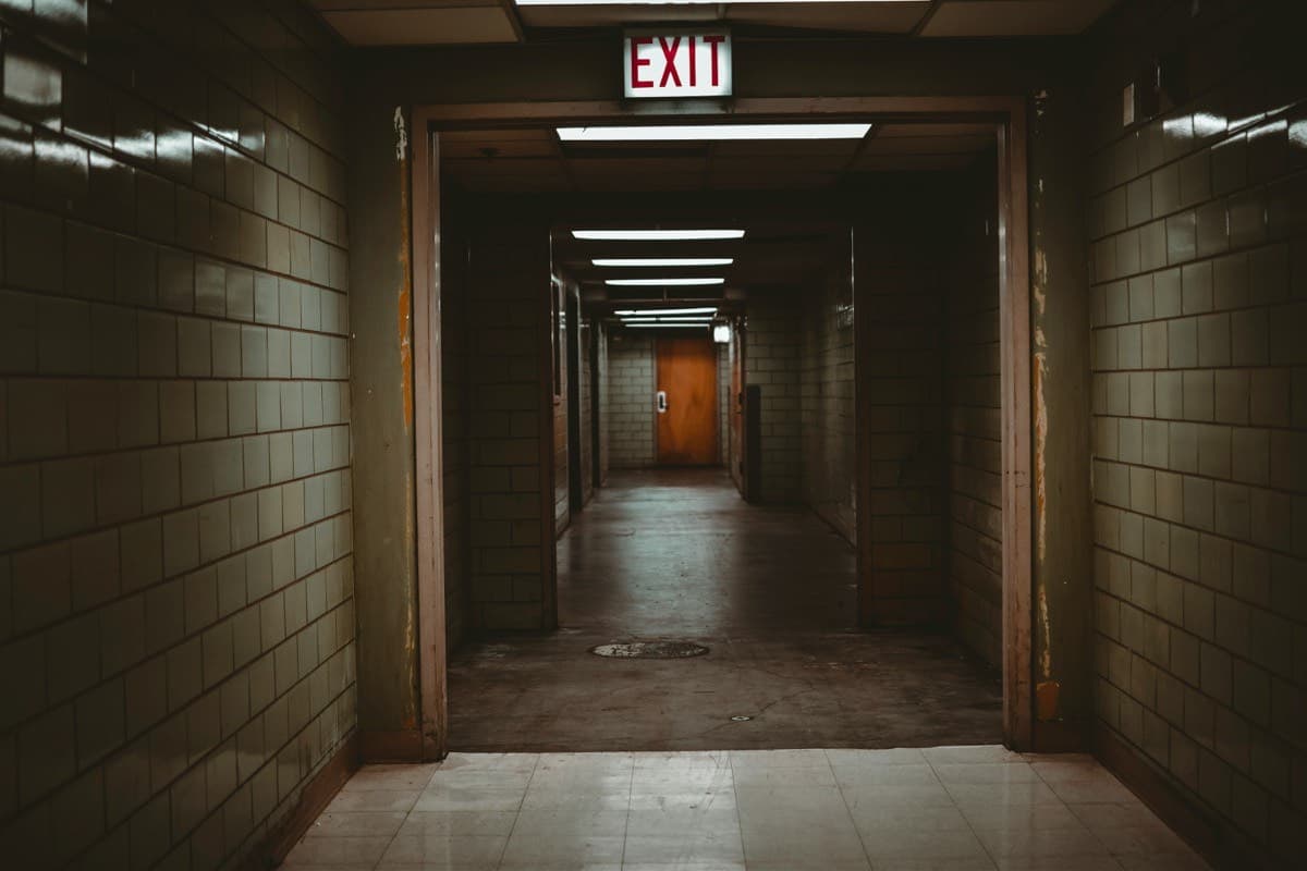 Dark corridor with EXIT sign and fire-rated door at the end